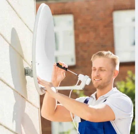 Fernsehtechniker justiert Satellitenschüssel an Hauswand